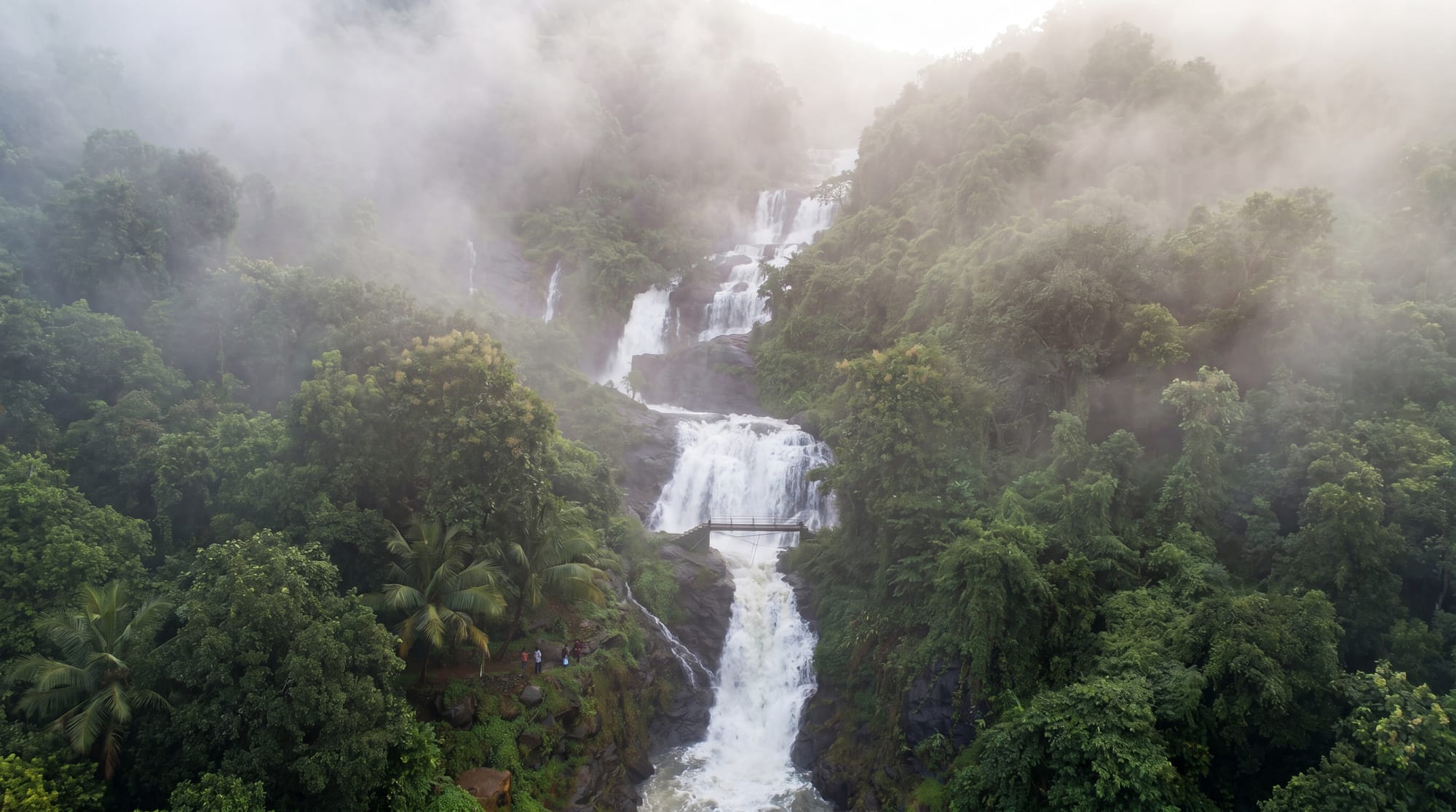 A misty multi-tier waterfall surrounded by rainforest in Yendayar, Kerala