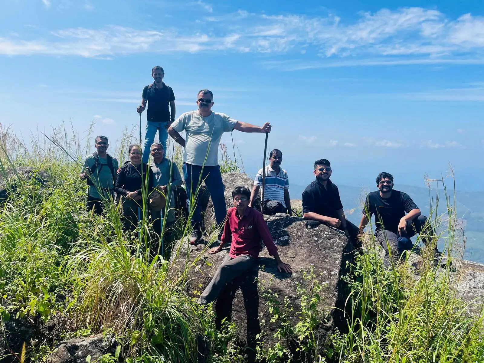 Trekkers resting on summit boulders at Muthukora Hills with panoramic views over the lowlands