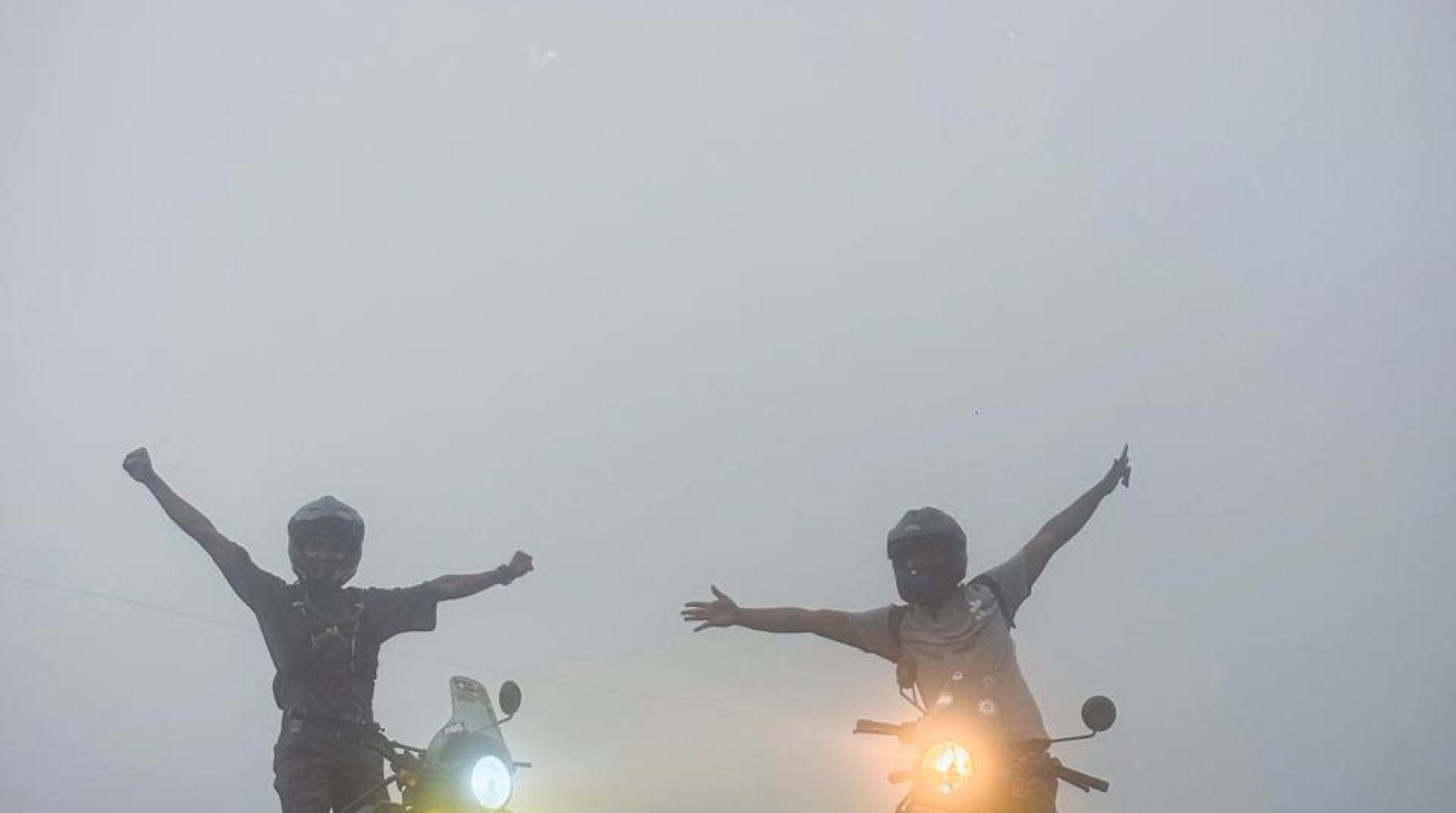Two Royal Enfield Himalayans with fog lights glowing in heavy mist on the rocky trail to Urumbikkara, Kerala