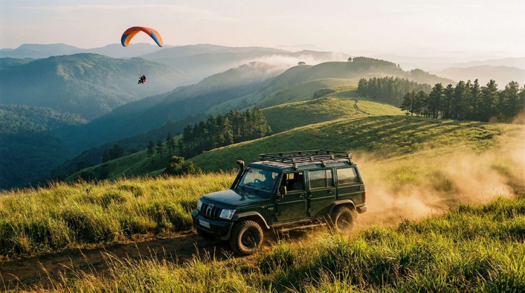 Tandem paraglider soaring over the green ridges of Kolahalamedu near Vagamon, Kerala