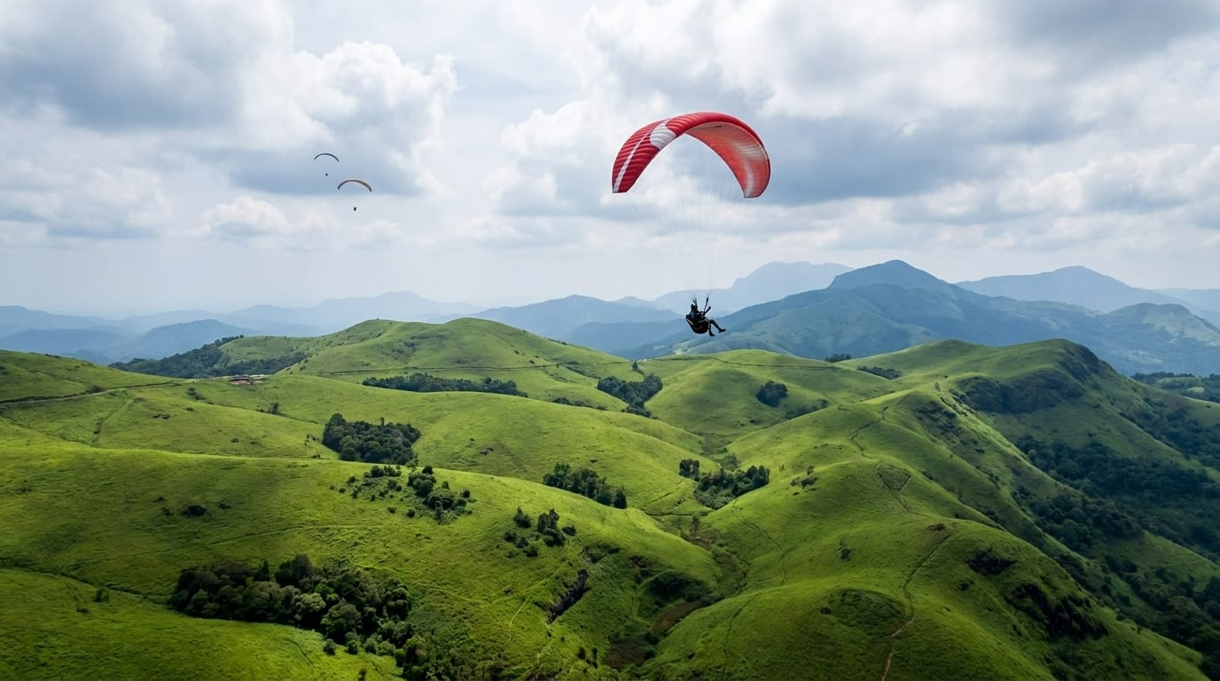 A paraglider soaring over the green rolling meadows of Vagamon, Kerala